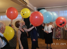 Widok tańczących członków Klubu Seniora trzymających balony